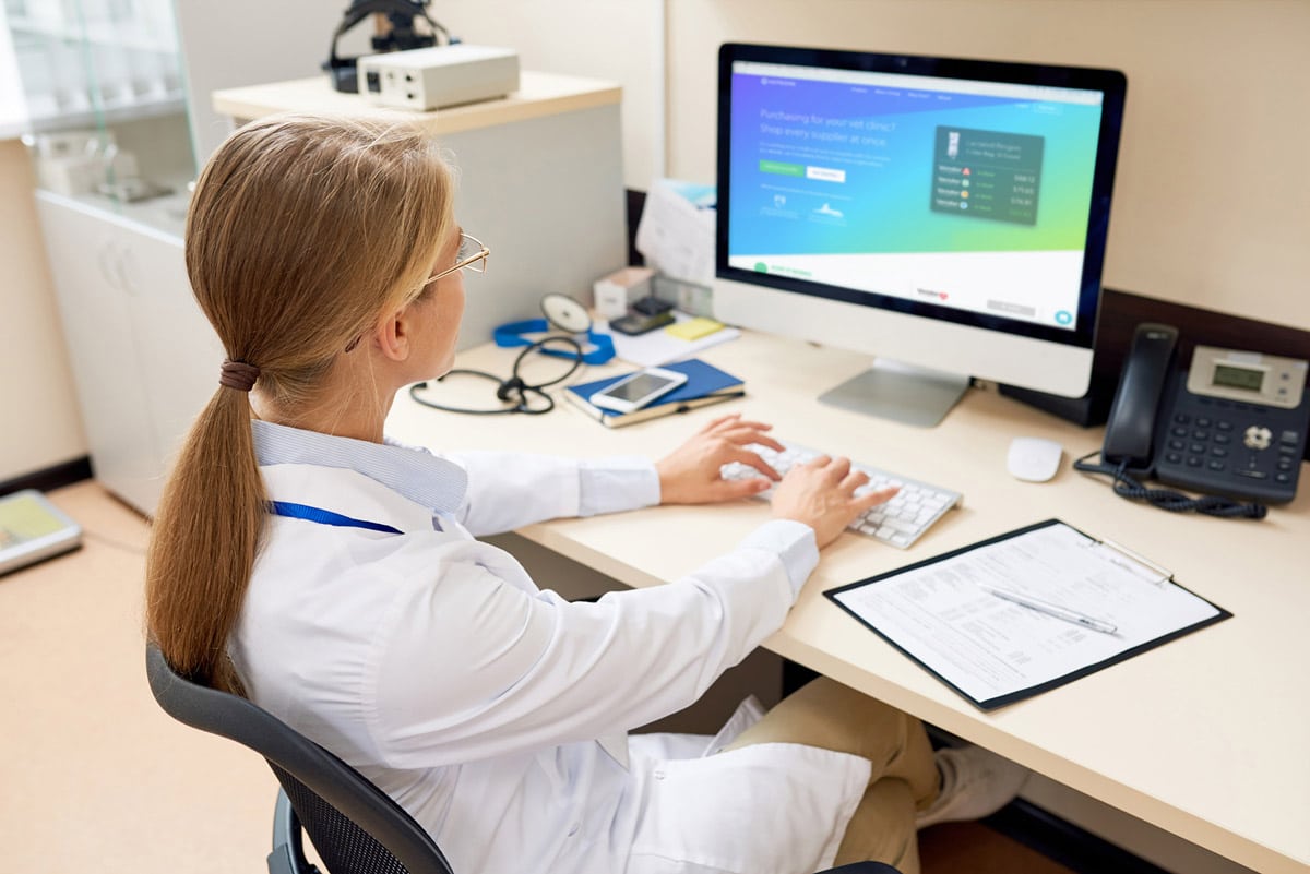 Veterinarian typing on a computer while seated at a desk